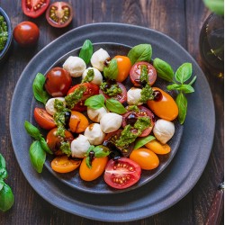 Salat Caprese med mozzarella, friske tomater, basilikum, oliven og pesto-dressing