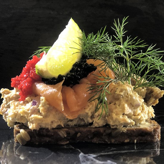 Laksesalat smørrebrød med varmrøget laks, kapers, løg, caviart og rugbrødschips Laksesalat smørrebrød med varmrøget laks, kapers, løg, caviart og rugbrødschips